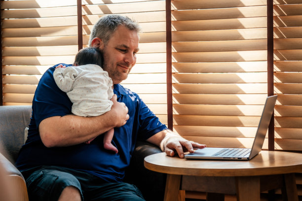 父亲带着刚出生的女婴使用笔记本电脑图片下载