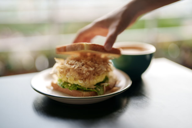 这张剪短的图片显示，一名女子正享受着一顿健康的早餐，手里拿着烤面包，上面放着炒鸡蛋和木鱼图片下载