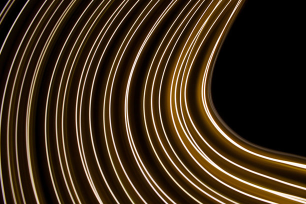 长时间曝光的照片。光画摄影-在黑色背景下，霓虹灯金色的漩涡波图片下载