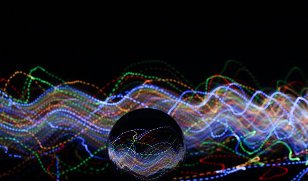 长时间曝光的照片。光画摄影-在玻璃球镜头后面的霓虹多色光的漩涡波。图片下载
