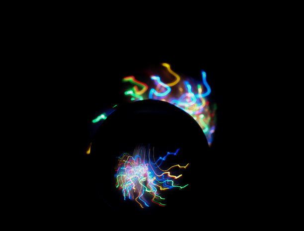 长时间曝光的照片。光画摄影-在玻璃球镜头后面的霓虹多色光的漩涡波。图片下载