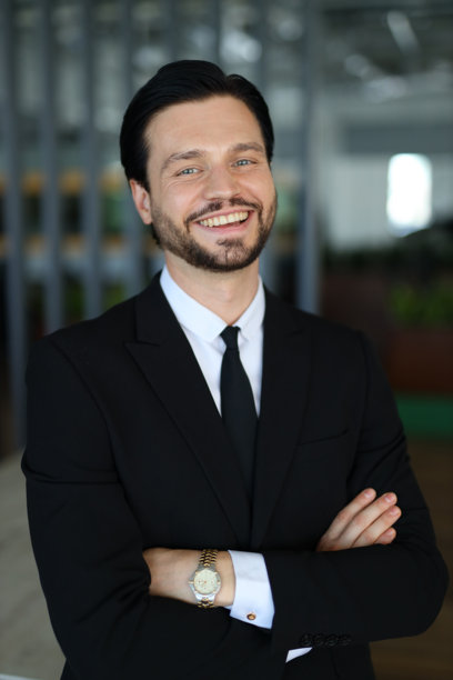 一个西装革履、戴着手表的男人面带微笑。他在摆姿势拍照图片下载