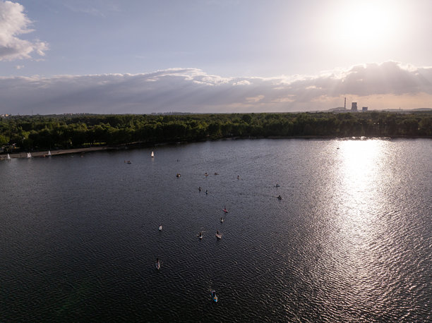 无人机拍摄的人们在湖上游泳的照片。一大群人坐在湖上的冲浪板上。站起来在湖上划桨。图片下载