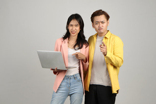 愤怒的印尼亚洲夫妇拿着笔记本电脑的肖像图片下载