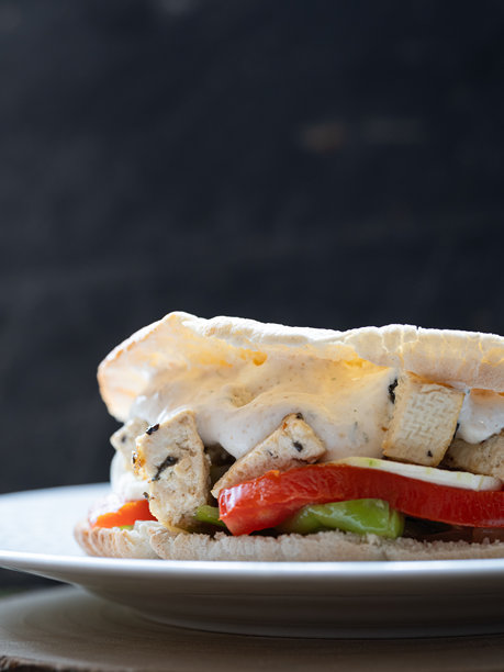 素食三明治的垂直照片，有烤蔬菜、豆腐和酸奶酱。黑色背景和复制空间图片下载