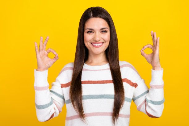 黑色头发的肖像照片迷人的快乐女孩可爱穿着毛衣显示两个ok的符号孤立在黄色背景图片下载