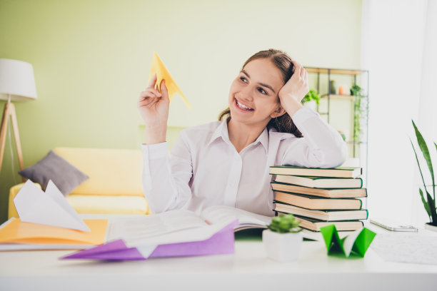 照片肖像十几岁可爱的女儿俏皮的纸飞机有乐趣穿校服远程教育家庭教育孤立的室内背景图片下载