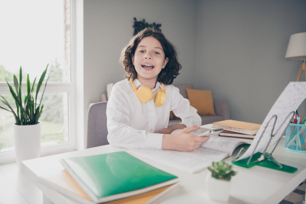 照片中可爱可爱的小男孩小学生穿着白衬衫在家里室内室内学习图片下载