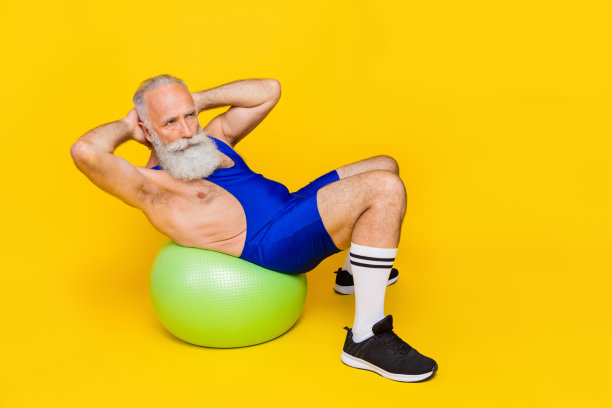 全身照片老复古的退休老人爷爷胡子灰白的头发练习躯干运动躺健身球严重孤立在黄色的背景图片下载
