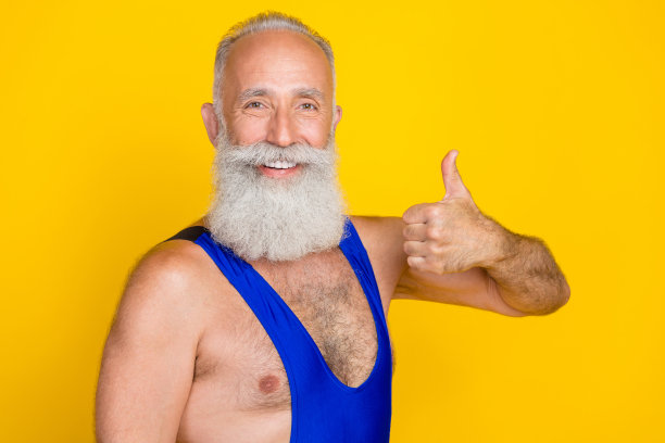 照片正面阳刚的专业教练穿着整体肌肉手臂大拇指向上享受健身有氧运动孤立在黄色背景。图片下载