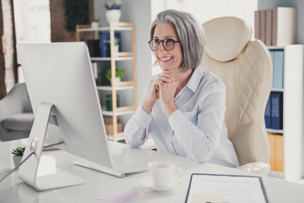 积极微笑的女老板的照片，穿着白衬衫，戴着眼镜，在室内工作场所的工作站阅读twitter电报facebook消息图片下载