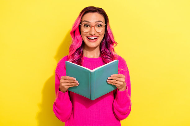 照片的兴奋时髦的女孩穿着充满活力的套头衫眼镜阅读书孤立的黄色背景图片下载