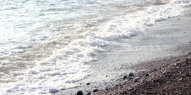 海上冲浪。日落时的水的照片。卵石沙滩上的小浪。图片下载