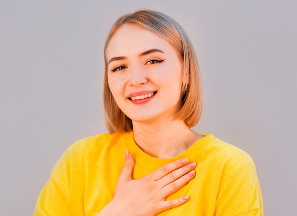 女人把手放在胸前。灰色背景隔离图片下载