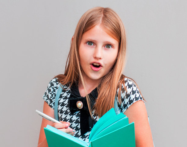 迷人的少女有着惊人的表情，迷人的外表，拿着钢笔的螺旋笔记本，想着写文章，隔着灰色的墙壁和空白的地方图片下载