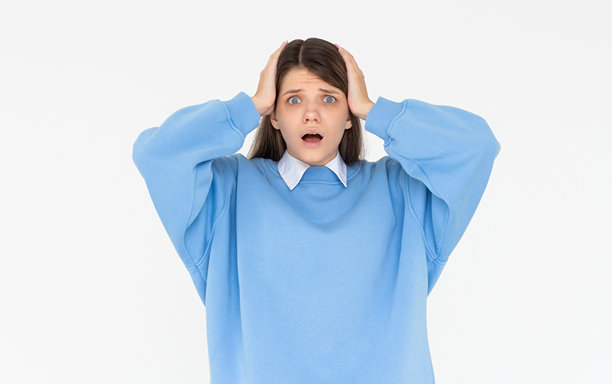 照片中震惊害怕的可爱女孩张开嘴双手头穿着蓝色运动衫孤立的白色背景图片下载