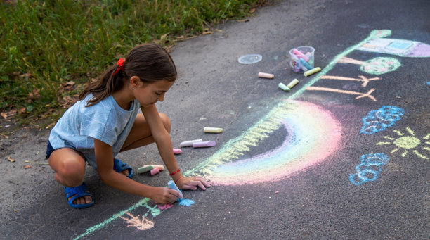 一个孩子在柏油路上用粉笔画画。美丽的图片。图片下载