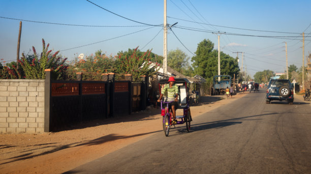 午后的阳光下，一名当地的自行车手在马达加斯加莫伦达瓦的街道上穿行，周围是日常的乡村生活图片下载