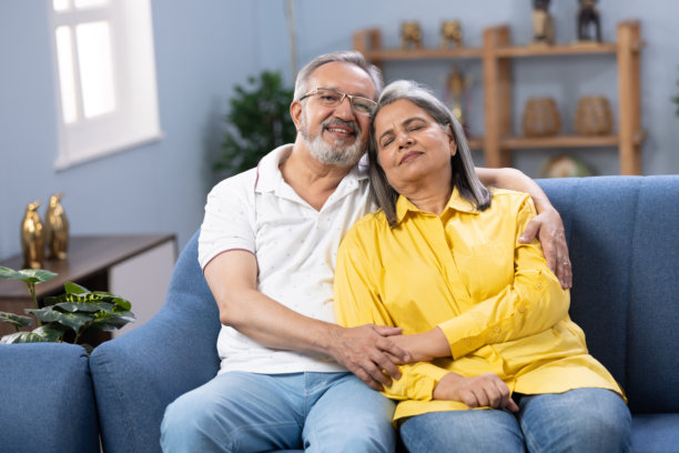 老夫妇闭上眼睛，放松在客厅沙发上舒适的午睡，轻松的生活方式和退休在家里，爱，照顾和睡在沙发上的老夫妇一起在公寓库存照片图片下载