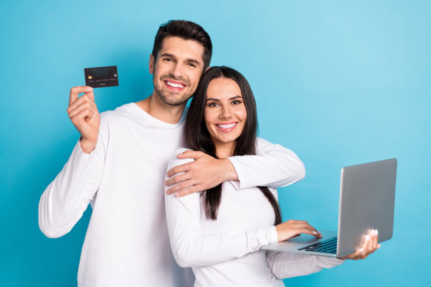 可爱的年轻男子的照片肖像女子笔记本电脑信用卡预订电子商务穿时髦的白色看起来孤立的蓝色背景图片下载