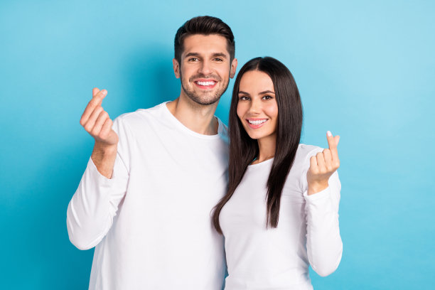 两个积极可爱的伴侣的照片，手臂的手指展示了韩国的爱的手势，在蓝色的背景隔离图片下载