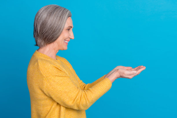 开朗的老人的侧面照片，牙齿微笑，双手握空的空间孤立在蓝色的背景图片下载