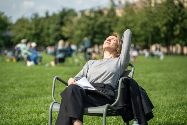 放松的女人在草坪上的城市椅子上休息，从远程工作中休息，闭着眼睛享受阳光图片下载