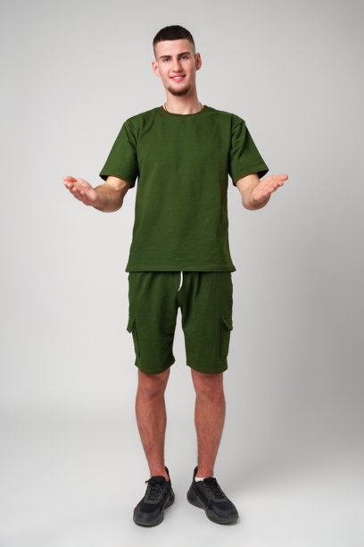 一个穿着绿色t恤的年轻人在白色背景前用双手打手势图片下载