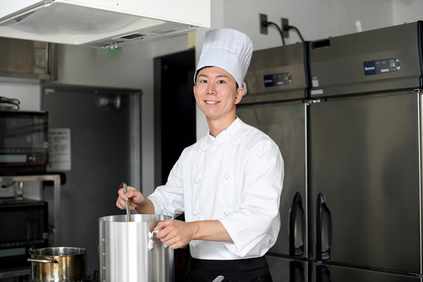 亚洲年轻男性厨师在厨房用大锅做饭图片下载