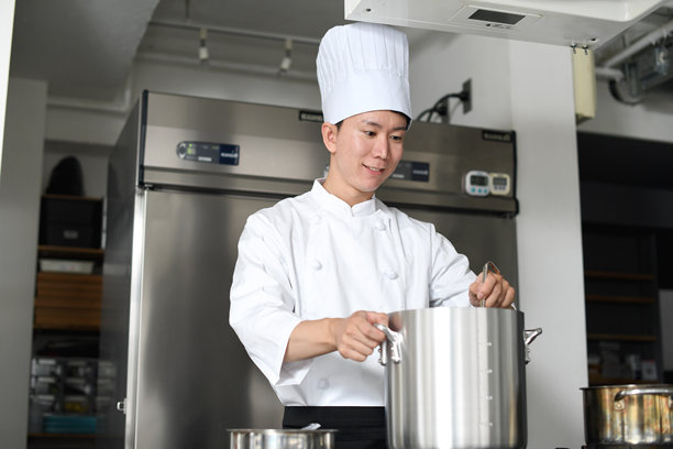 亚洲年轻男性厨师在厨房用大锅做饭图片下载