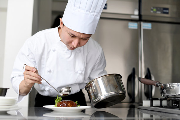 亚洲年轻男性厨师在厨房用盘子盛食物图片下载