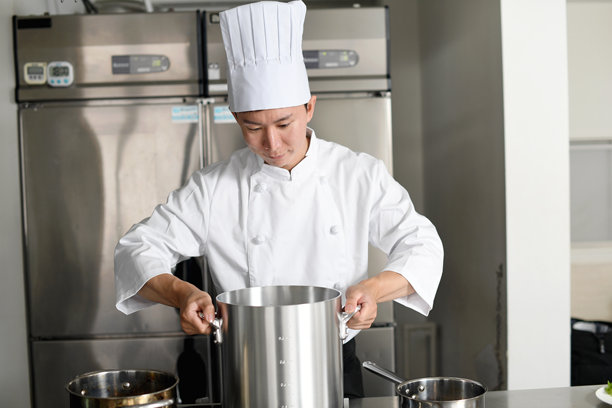 亚洲年轻男性厨师在厨房用大锅做饭图片下载