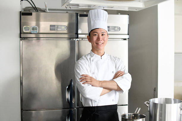 一位年轻的亚洲男厨师在厨房里交叉着双臂图片下载