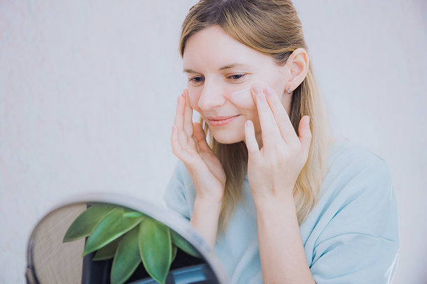 一个迷人的年轻女子在家里给脸上涂保湿霜的照片。护肤，用泡沫洁肤，用面霜保湿，美容和家庭护肤概念。图片下载