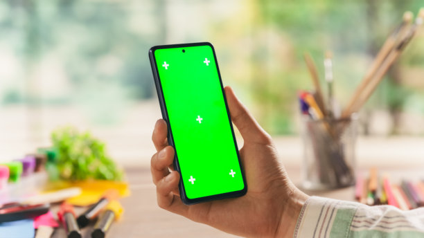 有创意的学者在智能手机上用模拟绿屏Chromakey显示屏检查社交网络帖子。照片模板与艺术设计广告和激励内容占位符图片下载