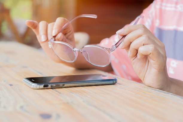 西班牙妇女的手拿着眼镜，准备戴在智能手机上享受社交。图片下载