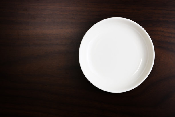 木桌背景上的白色空盘子。图片下载