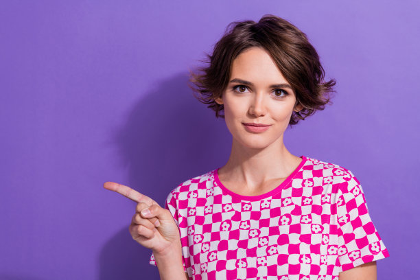 照片中可爱漂亮的女孩穿着新潮的格子衣服推荐品牌产品手臂直接空空孤立的紫色背景图片下载