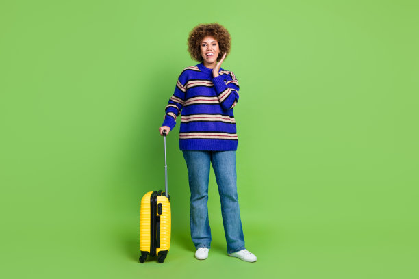 开朗可爱的女人穿着蓝色条纹时尚的衣服出国度假的照片孤立在绿色的背景图片下载