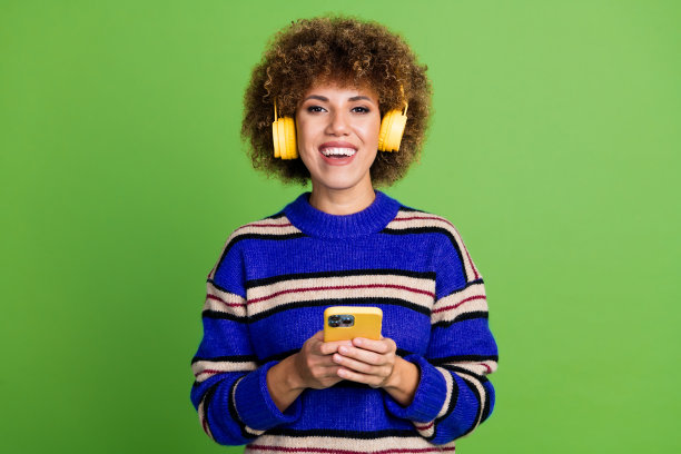 照片正面迷人可爱的女人穿着蓝色条纹衣服持有现代设备隔离在绿色背景图片下载