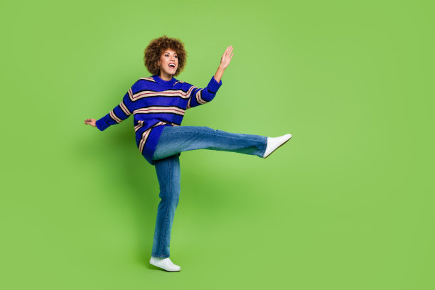 照片中可爱的积极可爱的女人穿着蓝色时尚的衣服跳舞冷看空空间孤立在绿色的背景图片下载