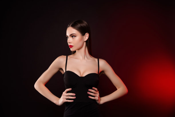 照片的女士在黑色连衣裙手腰看侧面孤立的黑暗霓虹色背景图片下载