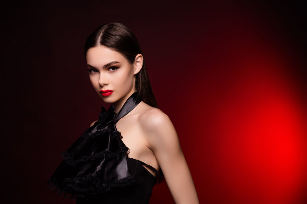 照片中的女士穿着黑色晚礼服，站在镜头前，站在文案空间，孤立的红色背景图片下载