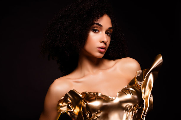 照片中的女士女孩看起来穿着金色闪闪发光的裙子，孤立的深色背景图片下载