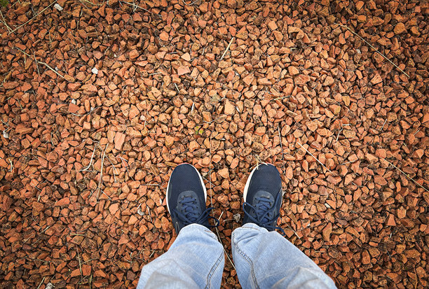 上面的照片是两只脚穿着运动鞋站在红色的石头地板上。有问题的概念。图片下载