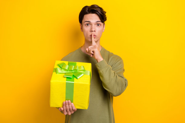 照片中的魅力男子穿着时髦的衣服，手臂触摸嘴唇嘘准备惊喜孤立在黄色背景图片下载