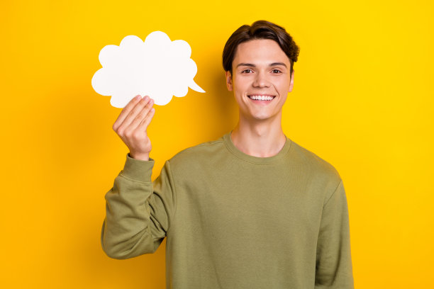 照片中，开朗的年轻人喜气洋洋地微笑着，手臂拿着纸云卡，孤立在黄色背景上图片下载