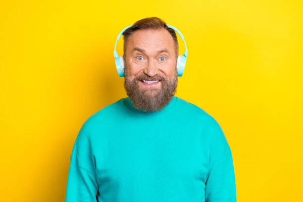 照片积极开朗的男人穿着时髦的衣服，听着喜欢的音乐，不错的音质隔离在黄色背景图片下载