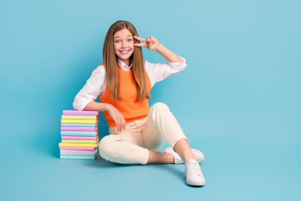 漂亮可爱的女士坐在地板上的全身照片，空白的空间v字靠近眼睛，在蓝色背景上孤立地宣传文学图片下载