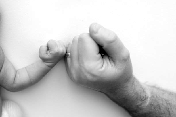 新生儿出生后紧紧抓住父母的手指。特写:孩子的小手和父母的手掌。育儿、育儿和保健理念。黑白照片。图片下载